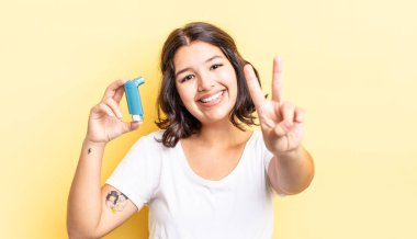 Genç İspanyol kadın gülümsüyor ve mutlu görünüyor, zafer ya da barış işareti yapıyor. astım konsepti