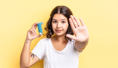 Genç İspanyol kadın ciddi görünüyor. Avuç içini gösteriyor. Durdurma hareketi yapıyor. astım konsepti