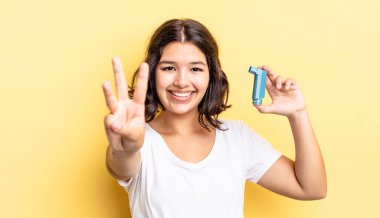 Genç İspanyol kadın gülümsüyor ve arkadaş canlısı görünüyor, üç numarayı gösteriyor. astım konsepti