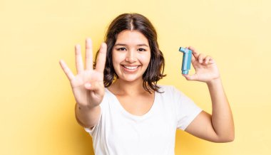 Genç İspanyol kadın gülümsüyor ve arkadaş canlısı görünüyor, dört numarayı gösteriyor. astım konsepti