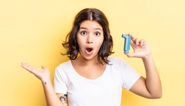 Genç İspanyol kadın şaşırmış ve şok olmuş görünüyor. Çenesi düşmüş ve elinde bir nesne tutuyor. astım konsepti