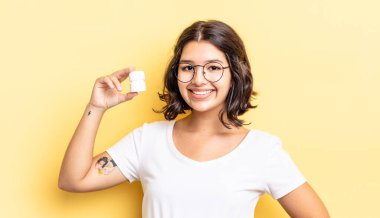 Genç İspanyol kadın mutlu bir şekilde gülümsüyor, eli kalçasında ve kendinden emin. hastalık hapları konsepti