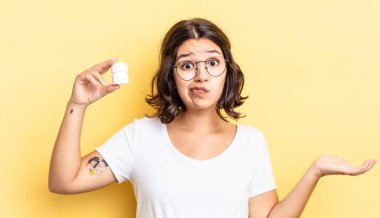 Genç İspanyol kadın şaşkın, şaşkın ve şüpheci hissediyor. hastalık hapları konsepti