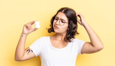 Genç İspanyol kadın şaşkın ve kafası karışık, kaşınan bir kafa hissediyor. hastalık hapları konsepti