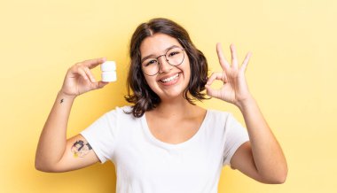 Genç İspanyol kadın kendini mutlu hissediyor, iyi bir jestle onaylıyor. hastalık hapları konsepti