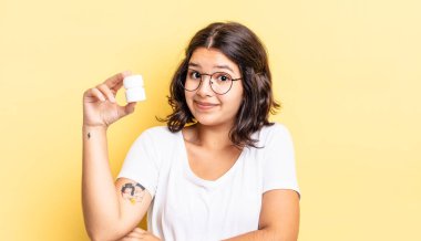 Genç İspanyol kadın omuz silkiyor, kafası karışık ve kararsız. hastalık hapları konsepti