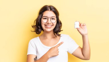 Genç İspanyol kadın neşeyle gülümsüyor, mutlu hissediyor ve bir tarafı işaret ediyor. hastalık hapları konsepti