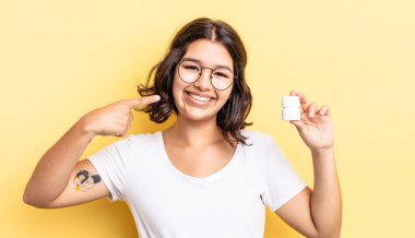 Genç İspanyol kadın kendine güvenerek gülümsüyor ve kendi gülüşünü gösteriyor. hastalık hapları konsepti