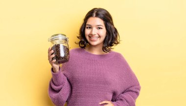 Genç İspanyol kadın mutlu bir şekilde gülümsüyor, eli kalçasında ve kendinden emin. kahve çekirdeği konsepti