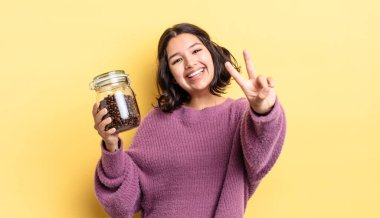 Genç İspanyol kadın gülümsüyor ve mutlu görünüyor, zafer ya da barış işareti yapıyor. kahve çekirdeği konsepti