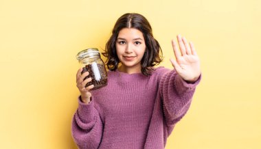 Genç İspanyol kadın ciddi görünüyor. Avuç içini gösteriyor. Durdurma hareketi yapıyor. kahve çekirdeği konsepti