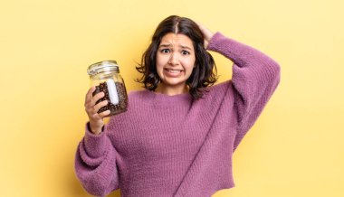 Genç İspanyol kadın stresli, endişeli ya da korkmuş hissediyor, elleri başının üstünde. kahve çekirdeği konsepti