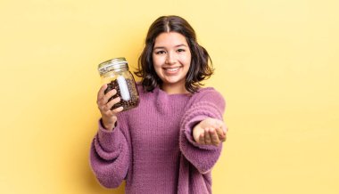 Genç İspanyol kadın mutlu bir şekilde gülümsüyor ve bir konsept sunuyor. kahve çekirdeği konsepti