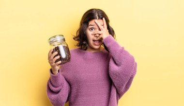 Genç İspanyol bir kadın şok olmuş, korkmuş ya da korkmuş görünüyor. Yüzü elle kapatılmış. kahve çekirdeği konsepti