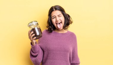 Neşeli ve asi tavırları olan, şaka yapan ve dilini dışarı çıkaran genç İspanyol bir kadın. kahve çekirdeği konsepti