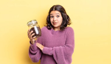 Genç İspanyol kadın omuz silkiyor, kafası karışık ve kararsız. kahve çekirdeği konsepti