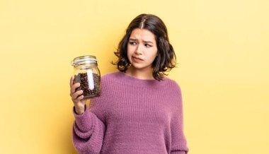 Genç İspanyol kadın üzgün, üzgün ya da kızgın hissediyor ve yana bakıyor. kahve çekirdeği konsepti