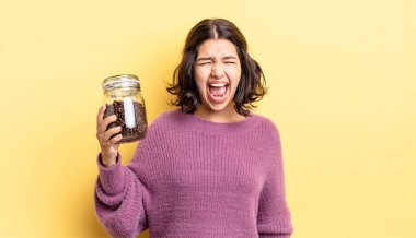 Genç İspanyol kadın agresif bir şekilde bağırıyor, çok kızgın görünüyor. kahve çekirdeği konsepti