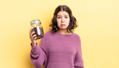 Genç İspanyol kadın üzgün ve mızmızlanıyor. Mutsuz bir bakışı var ve ağlıyor. kahve çekirdeği konsepti