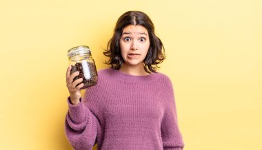 Genç İspanyol kadın şaşkın ve şaşkın görünüyor. kahve çekirdeği konsepti