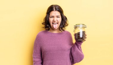 Genç İspanyol kadın iğreniyor, sinirleniyor ve dili dışarı çıkıyor. kahve çekirdeği konsepti