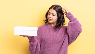 Genç İspanyol kadın şaşkın ve kafası karışık, kaşınan bir kafa hissediyor. boş kutu kavramı