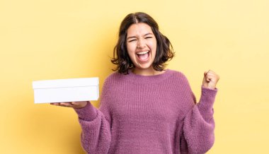 Genç İspanyol kadın şokta, gülüyor ve başarıyı kutluyor. boş kutu kavramı