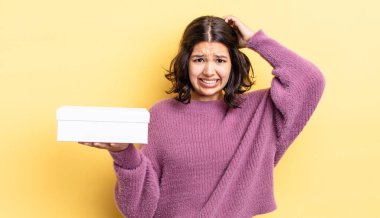 Genç İspanyol kadın stresli, endişeli ya da korkmuş hissediyor, elleri başının üstünde. boş kutu kavramı