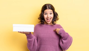 Genç İspanyol kadın kendini mutlu hissediyor ve heyecanla kendini işaret ediyor. boş kutu kavramı