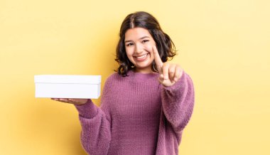 Genç İspanyol kadın gururla gülümsüyor ve kendinden emin bir numara oluyor. boş kutu kavramı