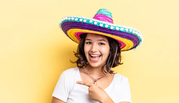 Młoda Latynoska Wyglądająca Podekscytowaną Zaskoczoną Wskazując Bok Meksykańska Koncepcja Kapelusza — Zdjęcie stockowe