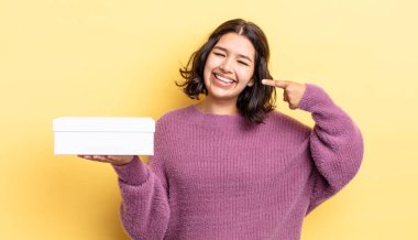 Genç İspanyol kadın kendine güvenerek gülümsüyor ve kendi gülüşünü gösteriyor. boş kutu kavramı