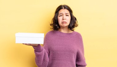 Genç İspanyol kadın üzgün ve mızmızlanıyor. Mutsuz bir bakışı var ve ağlıyor. boş kutu kavramı