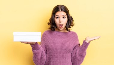 Genç İspanyol kadın şaşırmış ve şok olmuş görünüyor. Çenesi düşmüş ve elinde bir nesne tutuyor. boş kutu kavramı