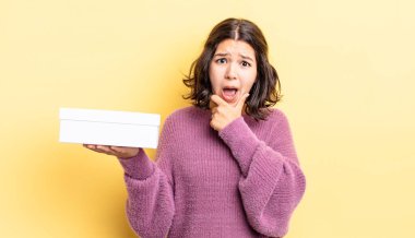 Ağzı ve gözleri sonuna kadar açık ve eli çenesinde olan genç İspanyol kadın. boş kutu kavramı