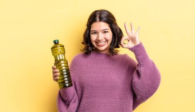 Genç İspanyol kadın kendini mutlu hissediyor, iyi bir jestle onaylıyor. Zeytin yağı kavramı