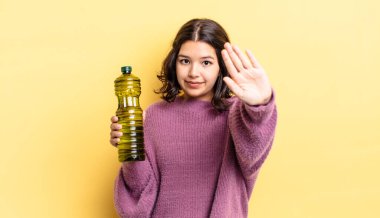 Genç İspanyol kadın ciddi görünüyor. Avuç içini gösteriyor. Durdurma hareketi yapıyor. Zeytin yağı kavramı