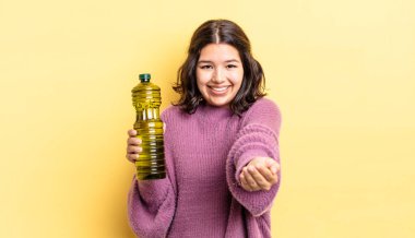 Genç İspanyol kadın mutlu bir şekilde gülümsüyor ve bir konsept sunuyor. Zeytin yağı kavramı