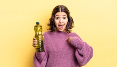 Genç İspanyol kadın kendini mutlu hissediyor ve heyecanla kendini işaret ediyor. Zeytin yağı kavramı