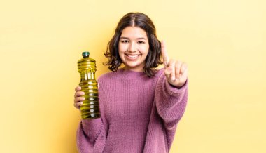 Genç İspanyol kadın gülümsüyor ve arkadaş canlısı görünüyor, bir numarayı gösteriyor. Zeytin yağı kavramı