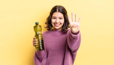 Genç İspanyol kadın gülümsüyor ve arkadaş canlısı görünüyor, dört numarayı gösteriyor. Zeytin yağı kavramı