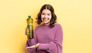 Genç İspanyol kadın neşeyle gülümsüyor, mutlu hissediyor ve bir konsept gösteriyor. Zeytin yağı kavramı