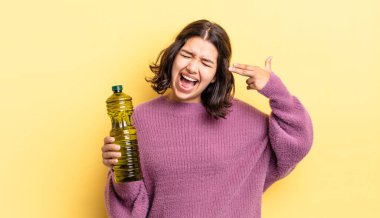 Genç İspanyol kadın mutsuz ve stresli görünüyor, intihar jesti silah işareti yapıyor. Zeytin yağı kavramı