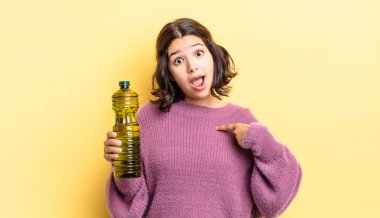 Genç İspanyol kadın şok olmuş ve ağzı açık, kendini işaret ederek şaşırmış görünüyor. Zeytin yağı kavramı