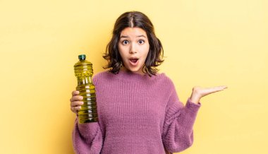 Genç İspanyol kadın şaşırmış ve şok olmuş görünüyor. Çenesi düşmüş ve elinde bir nesne tutuyor. Zeytin yağı kavramı