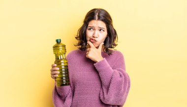 Genç İspanyol kadın düşünüyor, kuşkulu ve şaşkın hissediyor. Zeytin yağı kavramı