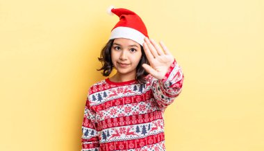 Genç İspanyol kadın ciddi görünüyor. Avuç içini gösteriyor. Durdurma hareketi yapıyor. Noel konsepti