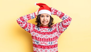 Genç İspanyol kadın stresli, endişeli ya da korkmuş hissediyor, elleri başının üstünde. Noel konsepti
