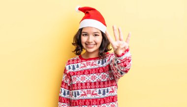 Genç İspanyol kadın gülümsüyor ve arkadaş canlısı görünüyor, dört numarayı gösteriyor. Noel konsepti