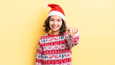 Genç İspanyol kadın gülümsüyor ve arkadaş canlısı görünüyor, bir numarayı gösteriyor. Noel konsepti